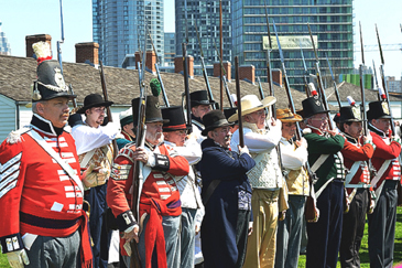 Re-enactors in regular uniforms and a militia dressed more casually present arms at Battle of York Day ceremonies at Fort York on 27 April 2013. Photo: Department of National Defence